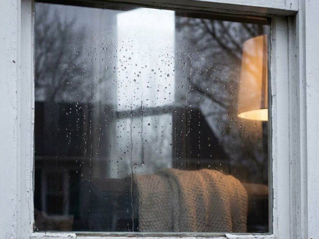 Rainy window with condensation and reflection