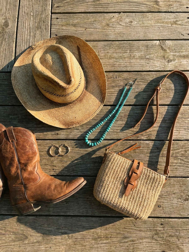 Flat lay of western concert accessories including boots, hat, and turquoise necklace.